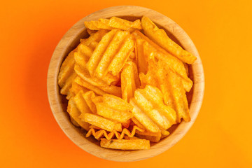 Crispy corrugated potato chips in wooden bowl