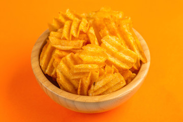 Crispy corrugated potato chips in wooden bowl