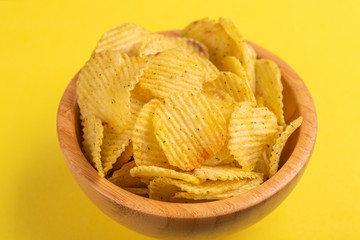Crunchy corrugated potato chips in wooden bowl