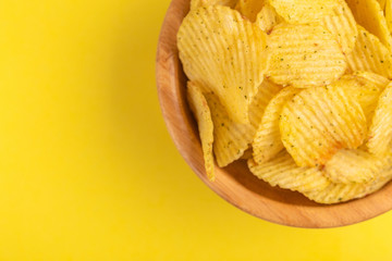 Crunchy corrugated potato chips in wooden bowl