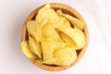 Tasty crispy potato chips in wooden bowl