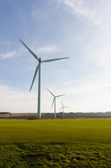 Fototapeta na wymiar mulitple wind turbines in a turfed field on a sunny day