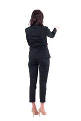 Back view of elegant business woman in black suit pointing at copyspace during presentation. Full body isolated on white background. 