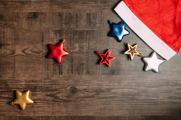 Santa hat with metallic stars on wooden background. Flat lay for Christmas and happy new year banner