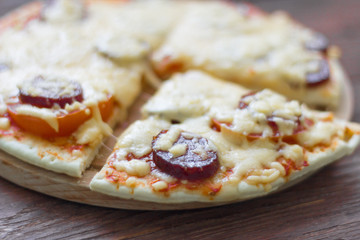 homemade hot pizza with salami, cheese and tomatoes on wooden background, ready to eat
