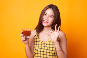 Young Asian woman show OK with tomato juice.