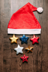 Obraz na płótnie Canvas Santa hat with metallic stars on wooden background. Flat lay for Christmas and happy new year banner