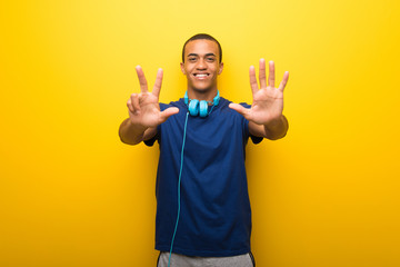 Fototapeta na wymiar African american man with blue t-shirt on yellow background counting eight with fingers