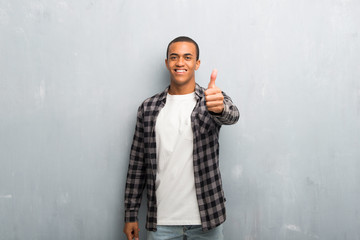 Young african american man with checkered shirt giving a thumbs up gesture because something good...