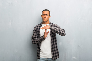 Obraz premium Young african american man with checkered shirt making stop gesture with her hand to stop an act