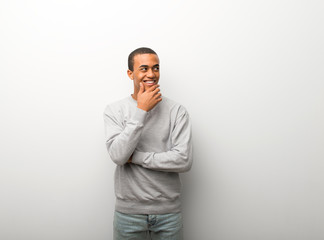 African american man on white wall background looking to the side with the hand on the chin