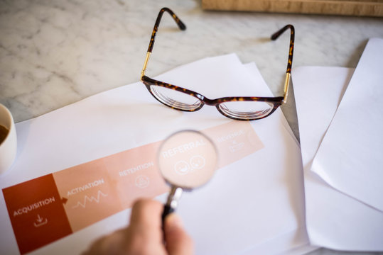 Male hand pointing at a printed AARRR Marketing sales funnel - Acquisition Activation Retention Revenue Referral