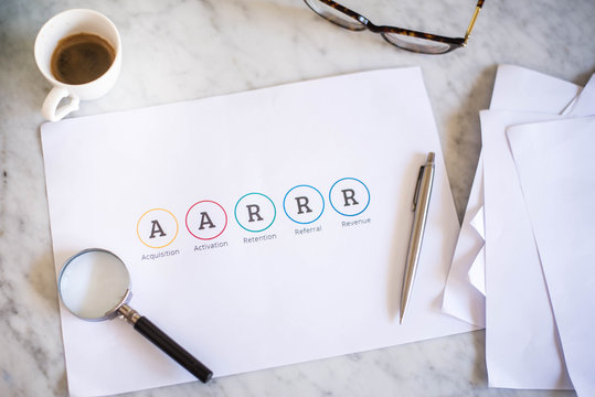 Male hand pointing at a printed AARRR Marketing sales funnel - Acquisition Activation Retention Revenue Referral