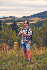 Hiker posing with knife on the belt in a meadow.