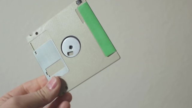 A 3.5 inch floppy disk held up and flipped over.  With a handwritten label describing the contents in pencil.