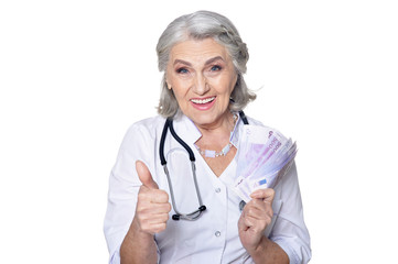 Portrait of mature female doctor with money, posing against white