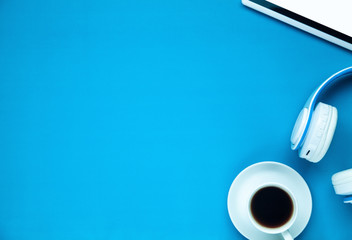Headphones, tablet and coffee on a blue background.