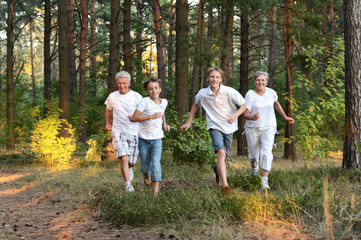 Naklejka na ściany i meble Cheerful boys with his grandparents having fun in summer forest