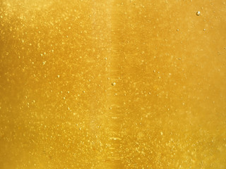 Tasty liquid background of fresh Golden honey with tiny bubbles glistening in the sun.
