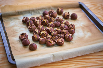 Close up of roasted chestnuts on baked paper after to be baked in owen, classic winter seasonal european delicatessen mainly for christmas or ingredient to cook sweets.