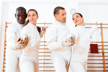 Men and women fencers practicing movements together at fencing workout