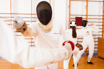 Athletes at fencing workout, practicing attack movements in duel