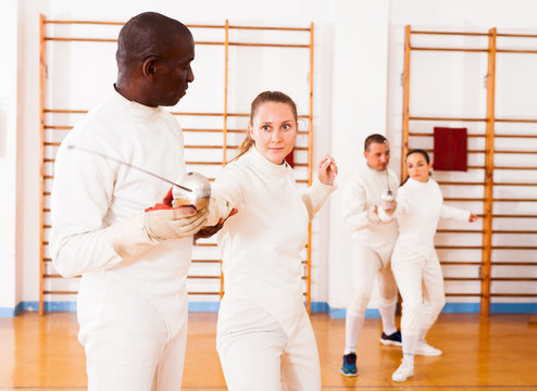 Female fencer practicing movements with african american male trainer - Powered by Adobe
