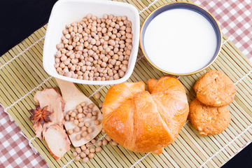 croissant baked bread with Milk in bowl soy bean in cup cookie and  spices on wooden bamboo. copy space for text. top view