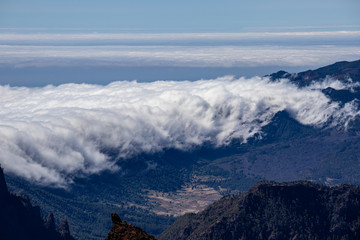Thick clouds in the valley. Panorama from the top of the mountain.