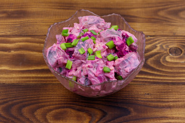 Obraz na płótnie Canvas Tasty salad with herring, beetroot, eggs, onion and mayonnaise on wooden table