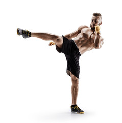Athletic man practicing tae-bo exercises, kicking forward with legs. Photo of sporty muscular male in sports clothes over white background