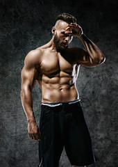 Fototapeta na wymiar Tired sporty man. Photo of strong man with naked torso on dark background. Strength and motivation.