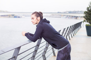 Woman using phone and listening to music with headphones on the boardwalk