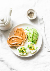 Peanut butter toasts, boiled egg with micro greens, avocado - healthy breakfast or snack on a light background, top view