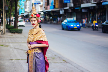 Woman wearing Thai style dress standing on the footpath in Bangkok, Thailand.