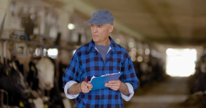 Thoughtful male farmer using digital tablet at stable