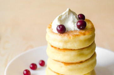 Cottage cheese pancakes with sour cream and berries on rustic background. Syrniki. Russian food. Copy space