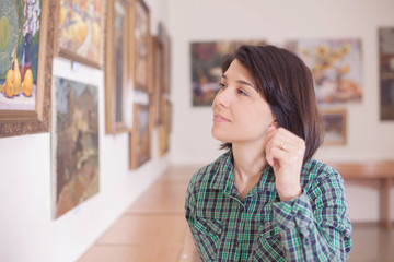 A young beautiful woman looking at painting.