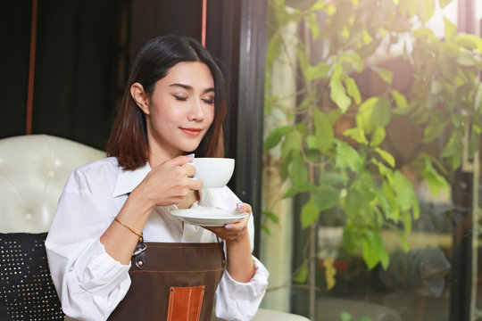 Closeup of a asian woman holding and drinking hot coffee with feeling good.