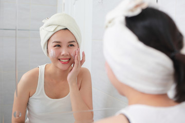 Woman happy cleanses the skin with foam on sink.