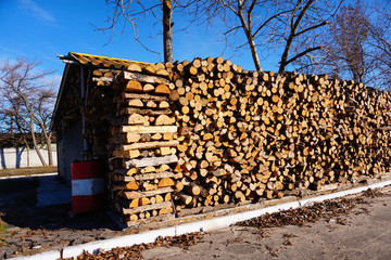 Sawed boards and logs for heating the stove, firewood is folded and lie under the open air on the street.