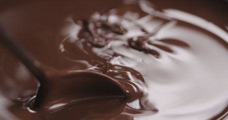 closeup stirring melted dark chocolate with spoon