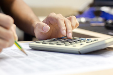 Close-up Businessman accounting using calculator for calculating finance and holding pencil checking documents financial report on desk office. business financial accounting concept.