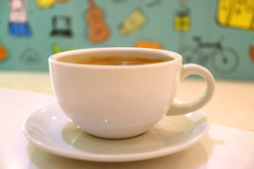 Closed up hot coffee in a white cup with blurred colorful wall paper in background