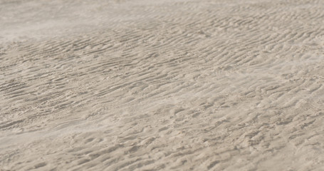 wind blows sand on a beach at midday
