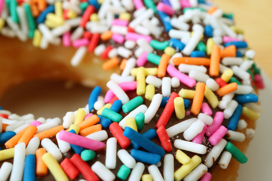 Closed up chocolate glazed doughnut topped with colorful sprinkles 