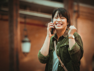 Asian woman using smartphone with happy mood in shopping mall