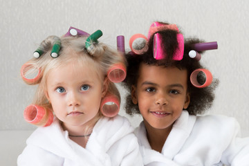 Girls friends together took a bath shower. Little girls of different nationalities in white coats with hair curlers.