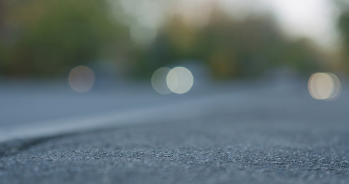 Low Angle Shot Of Blurred Moving Cars On City Street With Closeup Focus On Sidewalk