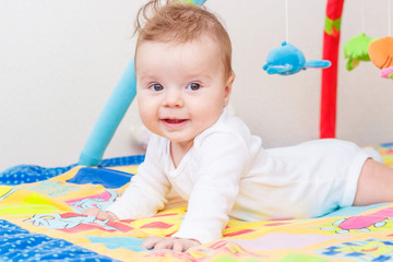 Playing little child on the colored mat for developing